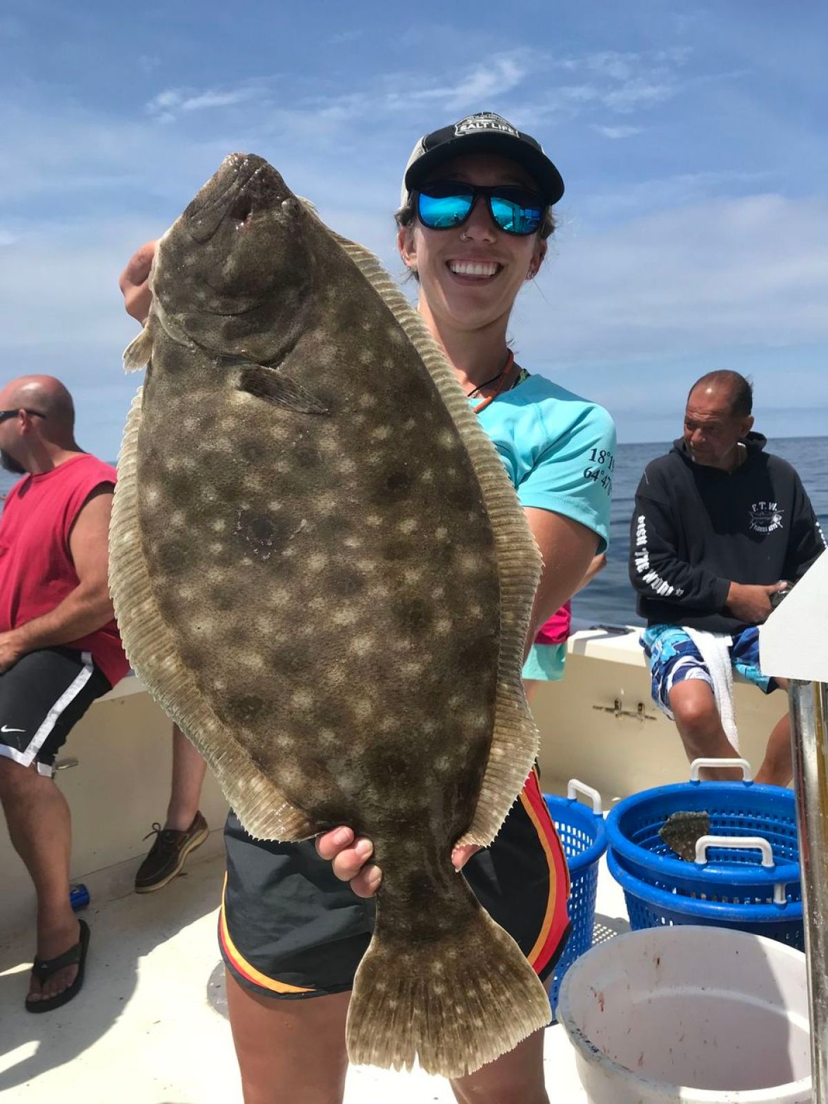 a group of people standing next to a person holding a fish